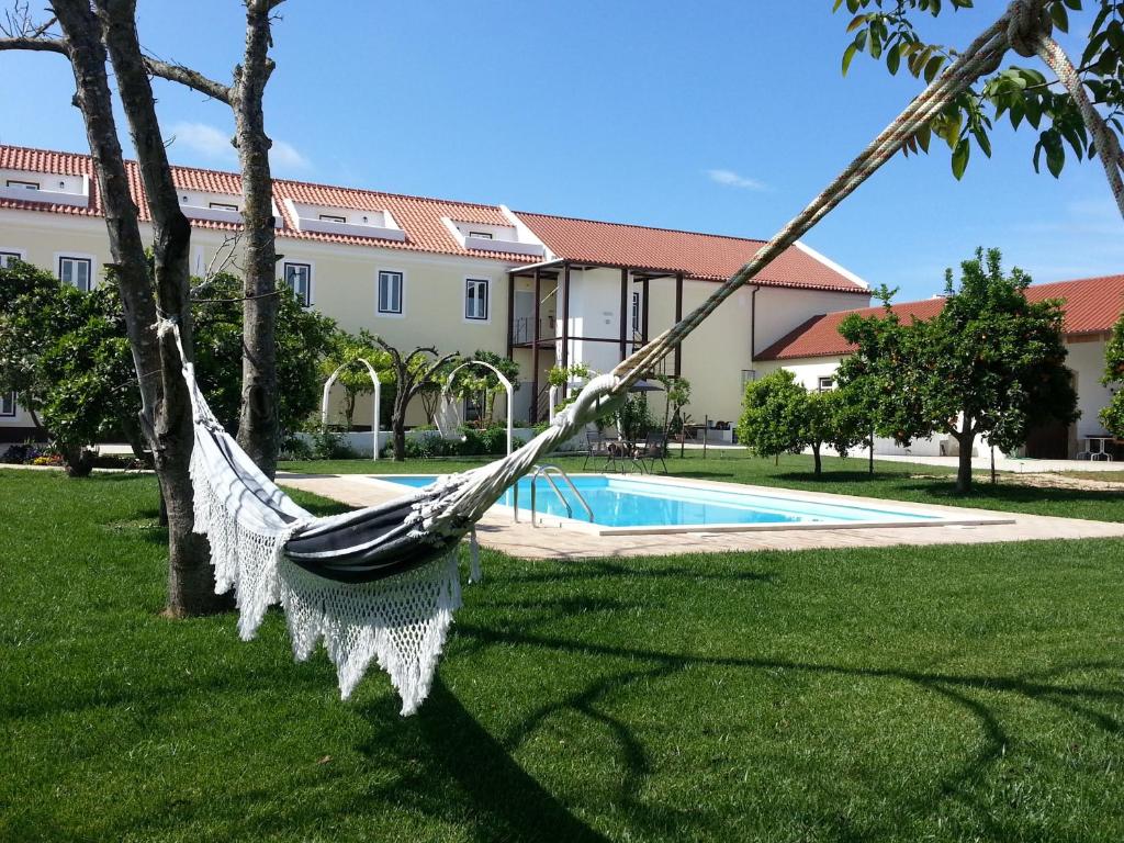 São Domingos卡萨斯莫阿根乡村民宿的吊床挂在树上,在带游泳池的院子中