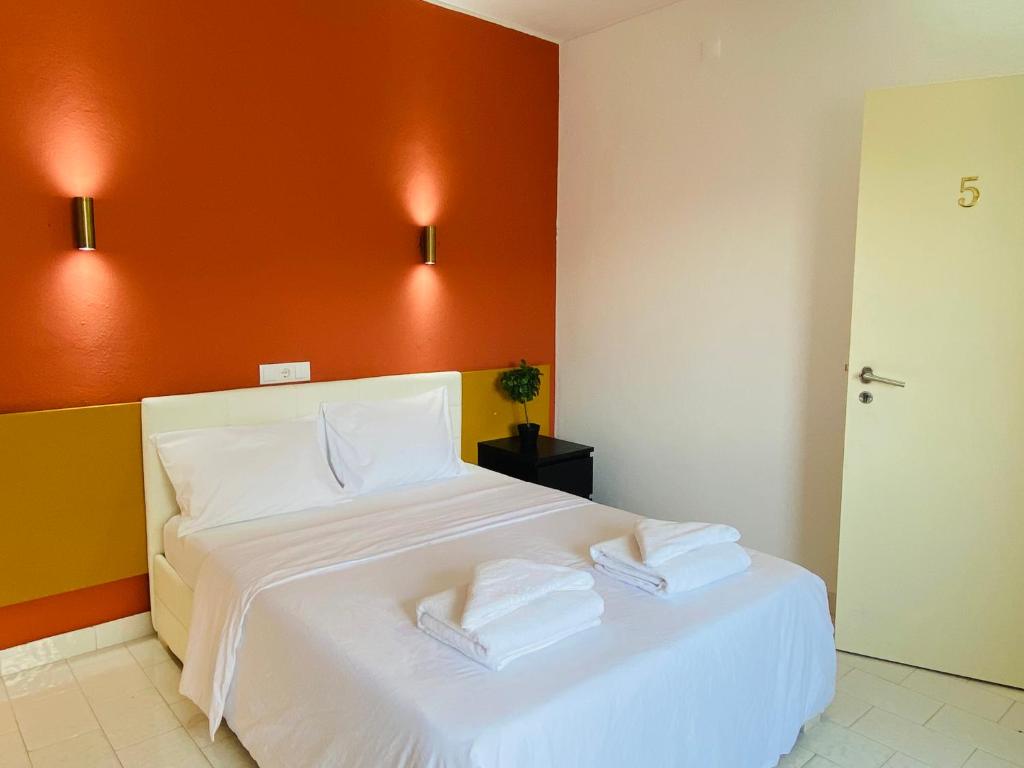 卡帕里卡海岸Central Atlantic Beach Guesthouse的一间卧室配有一张白色的床和橙色的墙壁