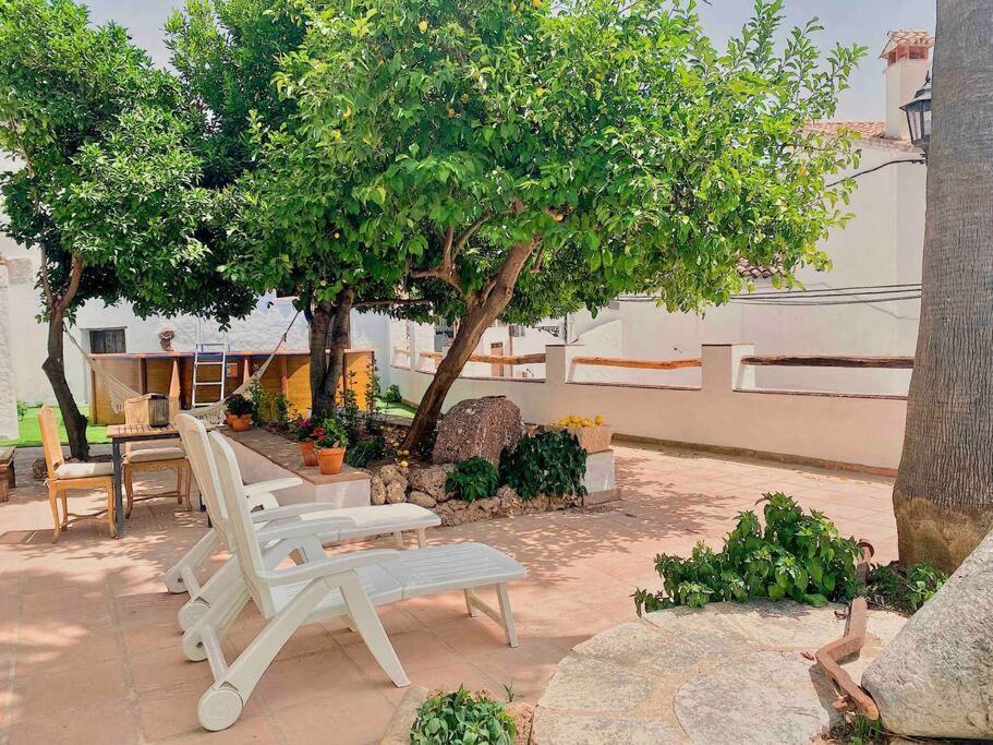 BenadalidLa Palmera. Casa rural con piscina privada.的一组白色的椅子和一张桌子,一棵树