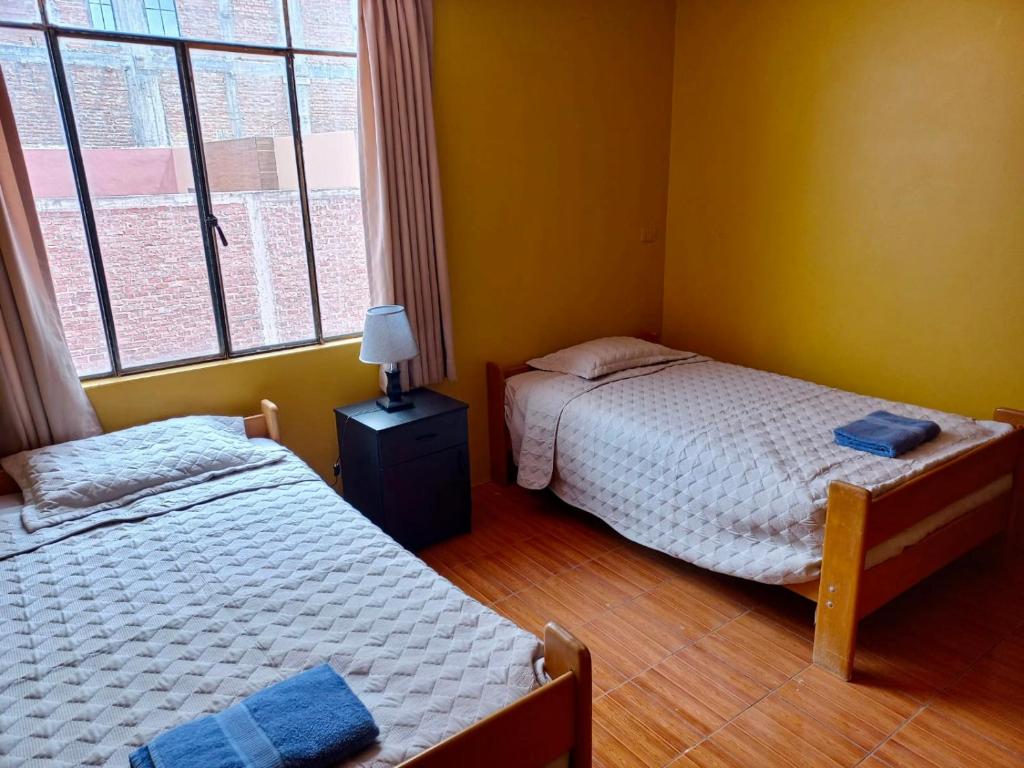 阿亚库乔Duplex amoblado en el corazón de Ayacucho的一间卧室设有两张床和窗户。