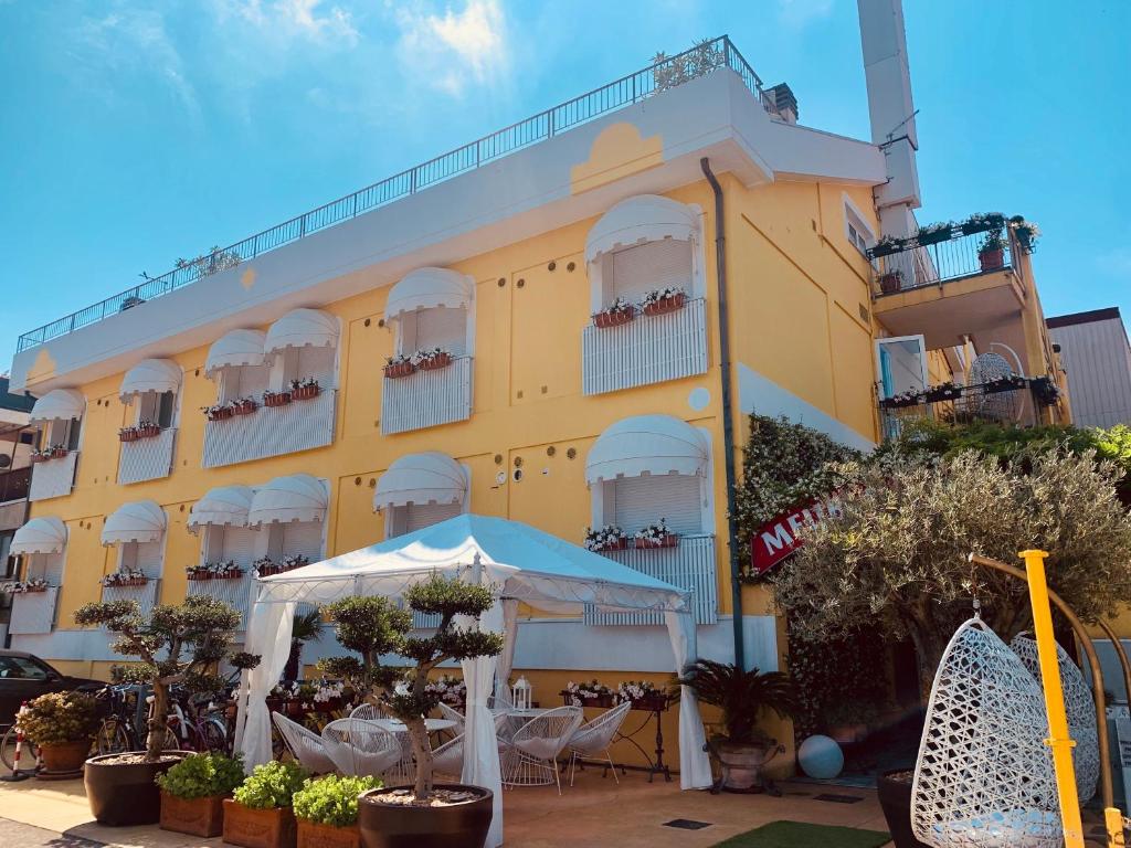 格拉多姆布勒黎波里酒店的前面设有桌椅的黄色建筑