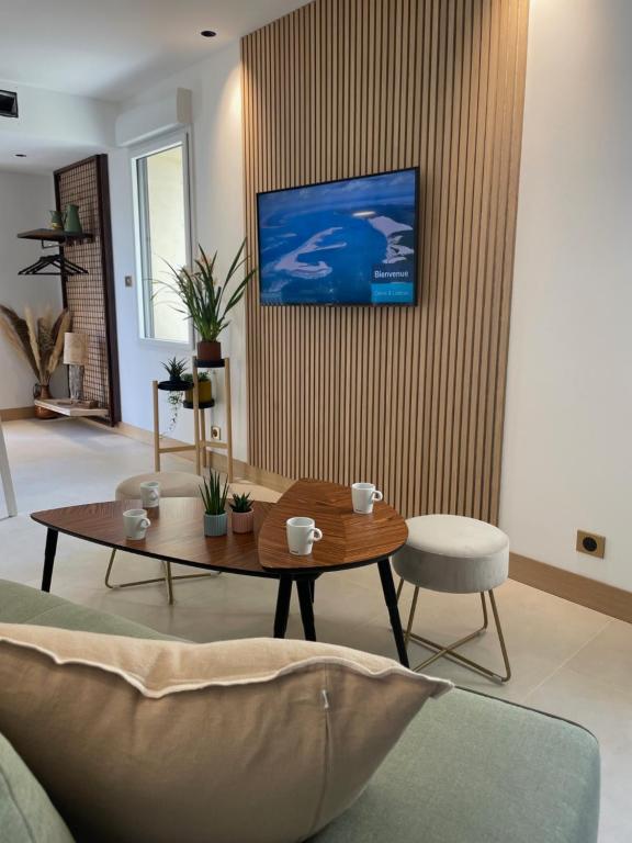 卡马尔萨克Appartement Neuf et Design的客厅配有桌子,墙上配有电视