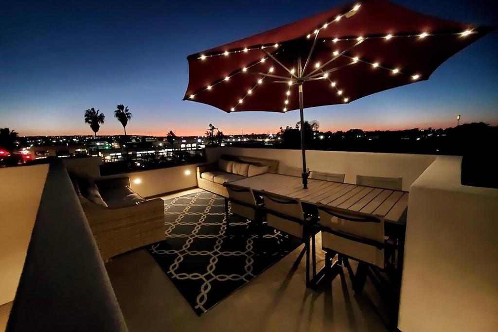 圣地亚哥Modern comfort, prime location, 360 views, 4 BR entire house的屋顶露台配有遮阳伞和灯