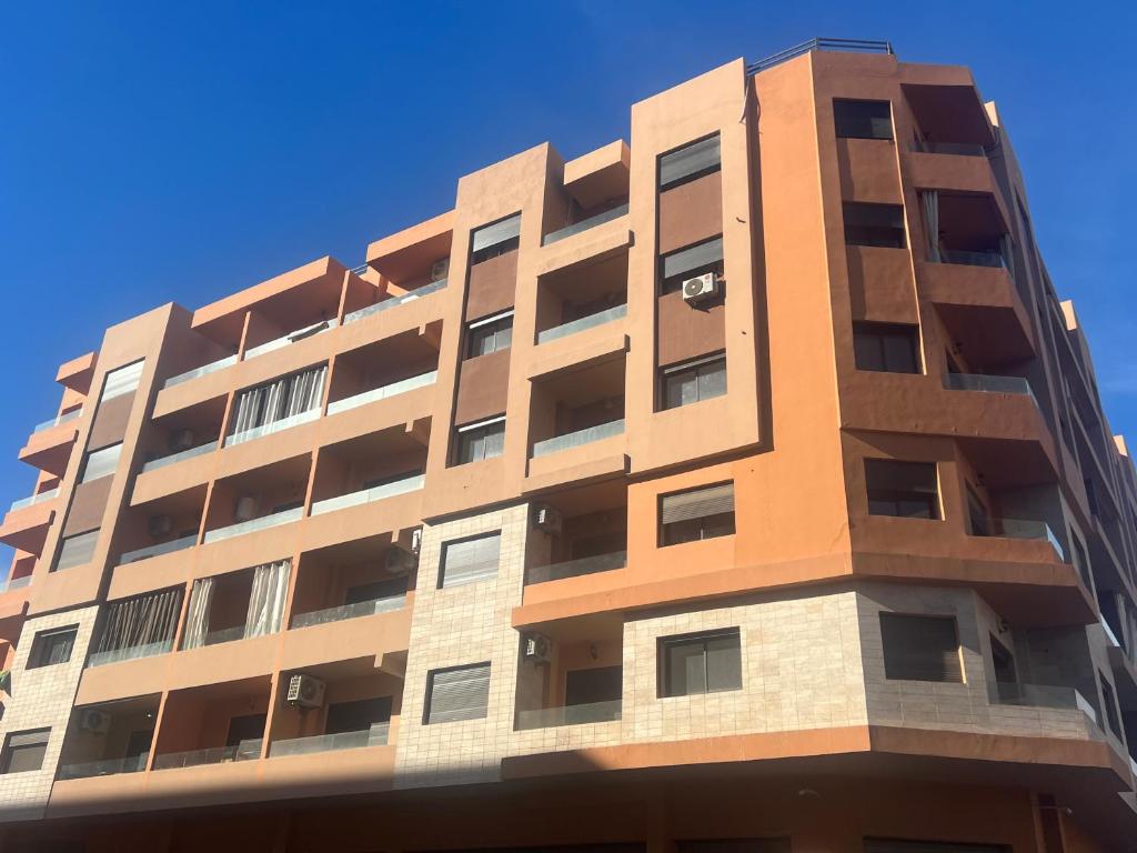 马拉喀什Luxury apartment Gueliz (2 min walk from Train Station)的蓝色天空下方的高公寓
