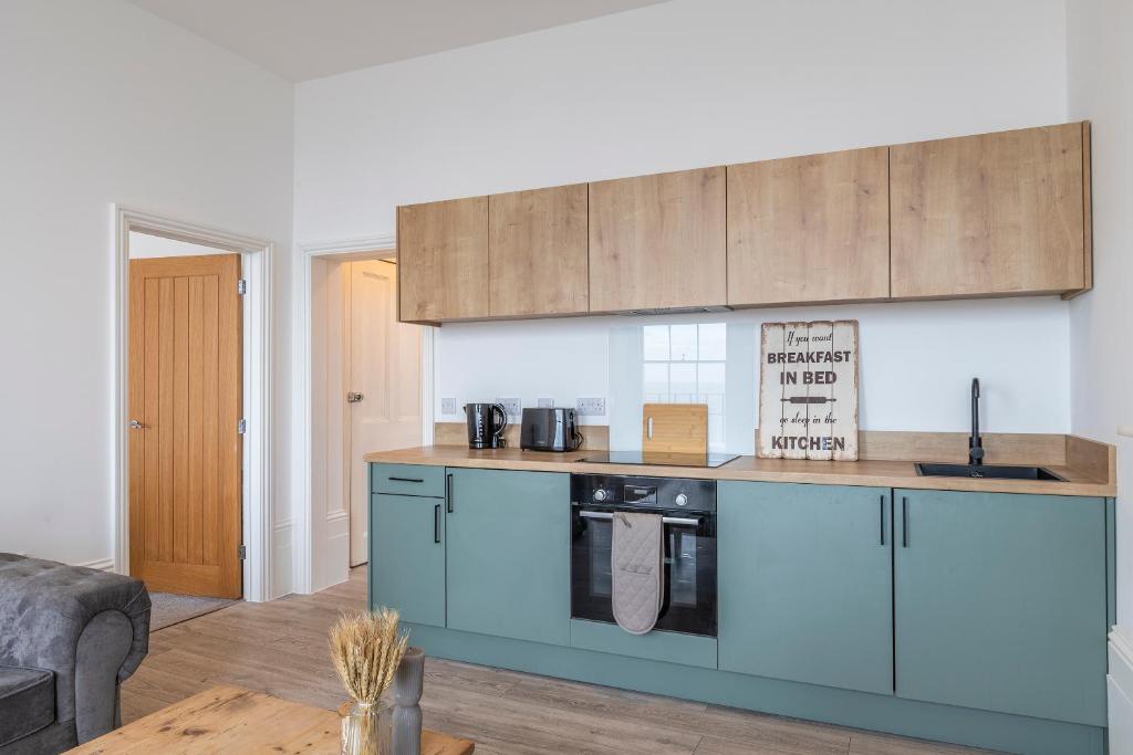 KentSeaside Bliss - Seafront Apartments的客厅里带蓝色橱柜的厨房