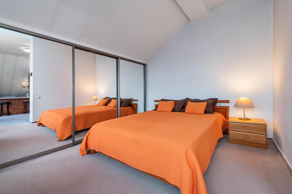 考纳斯Charming Old town apartment by Polo Apartments的一间卧室配有两张带橙色床单的床