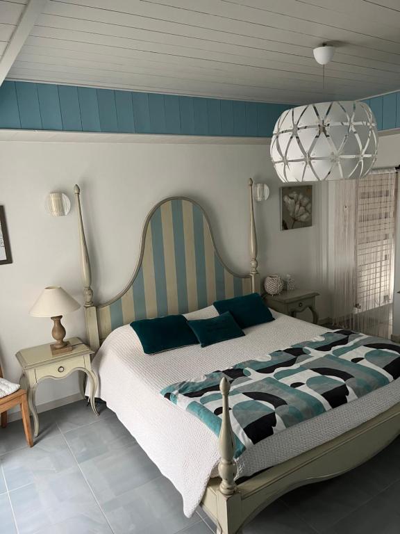 Le Grand VieilChambres d'hôtes LES CHENES VERTS的一间卧室配有一张大床和一个吊灯。