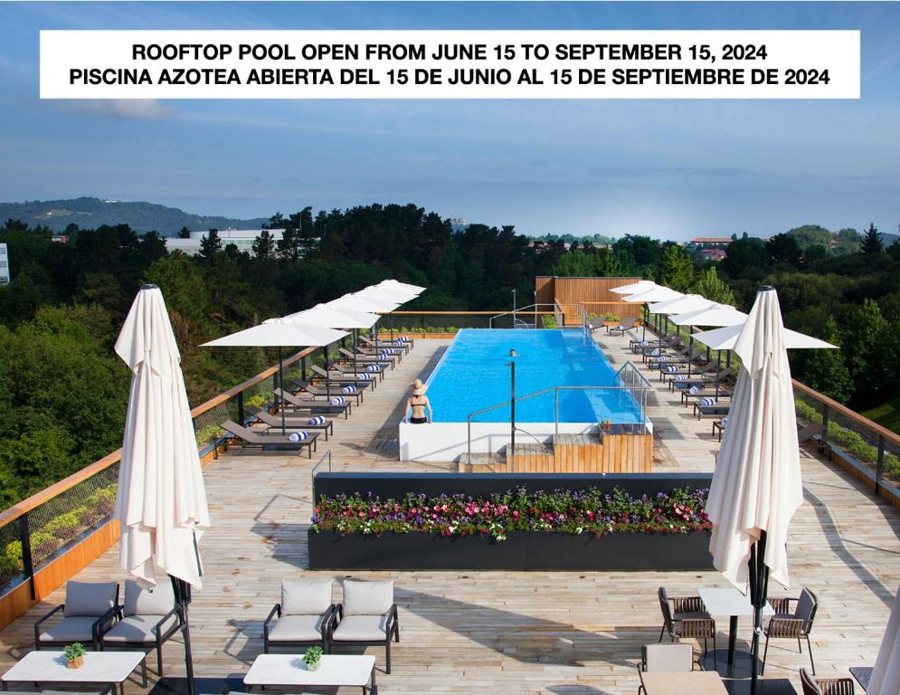 圣塞瓦斯蒂安Hotel Arima & Spa - Small Luxury Hotels的庭院内一个带椅子和遮阳伞的游泳池
