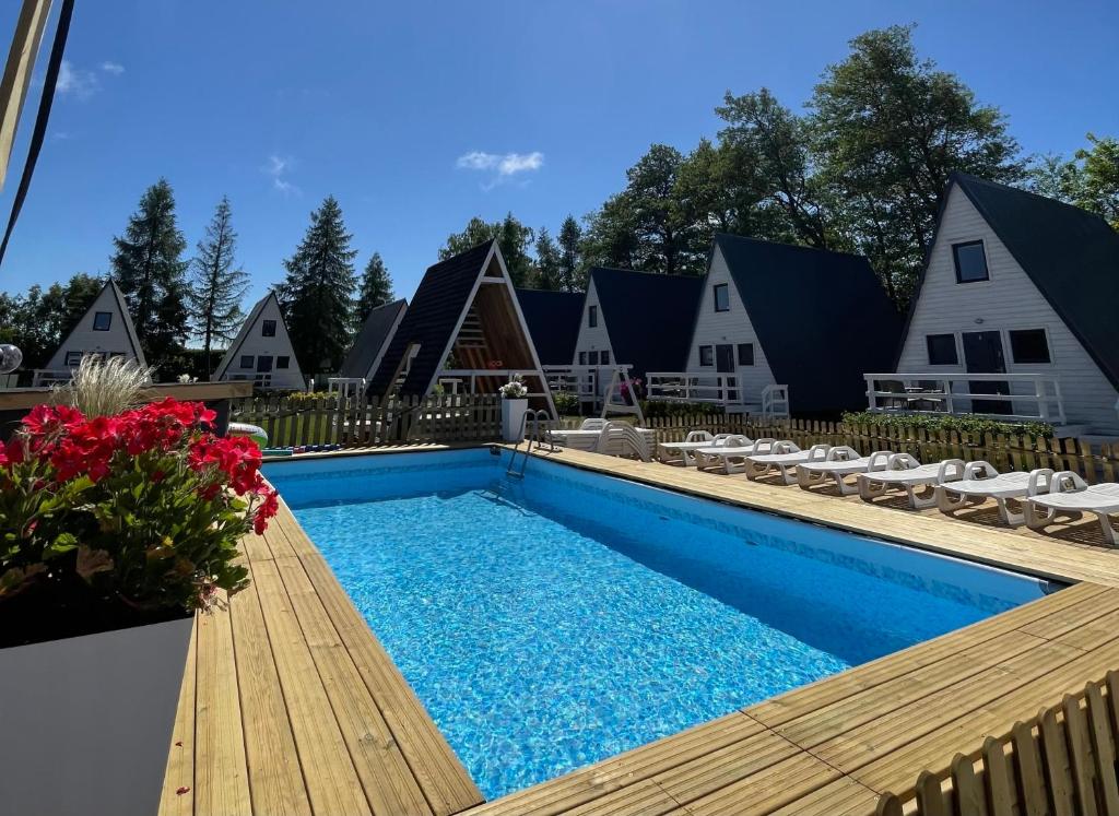 韦巴Soul Camp Nowęcin的一个带木制甲板的游泳池;有些房子