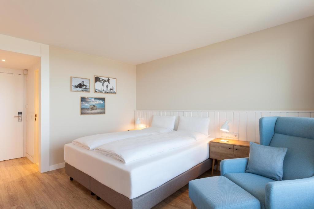 韦斯特兰Wyn. Strandhotel Sylt的一间卧室配有一张床和一张蓝色椅子