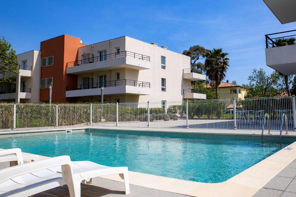曼德琉-拉纳普勒Comfort Aparthotel Cannes Mandelieu的大楼前的游泳池
