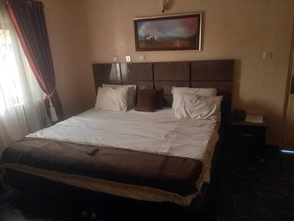奥韦里The Resident Hotel的卧室配有一张带白色床单和枕头的大床。