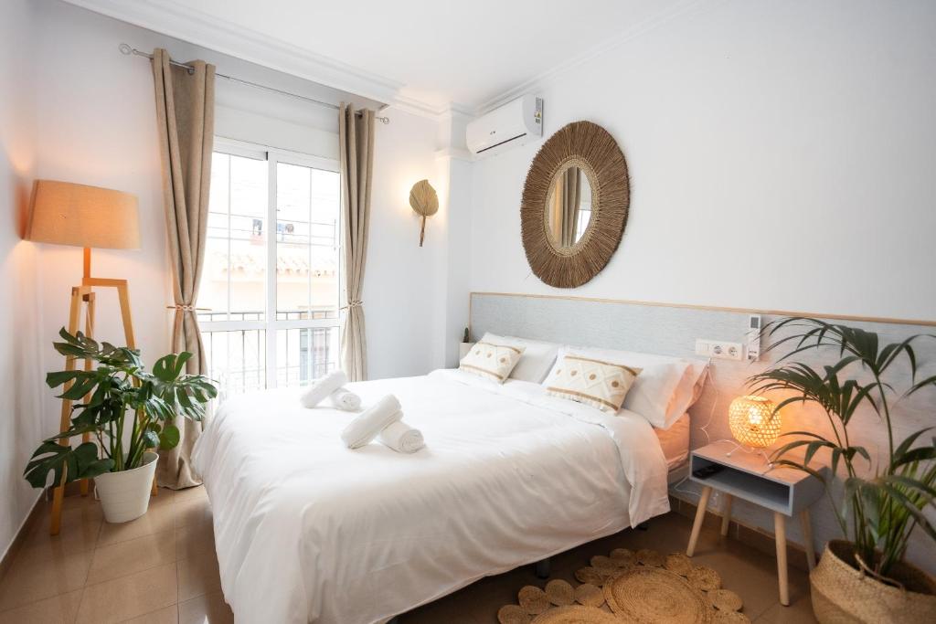 内尔哈Naim Guest House Nerja的白色的卧室设有一张大床和一个窗户