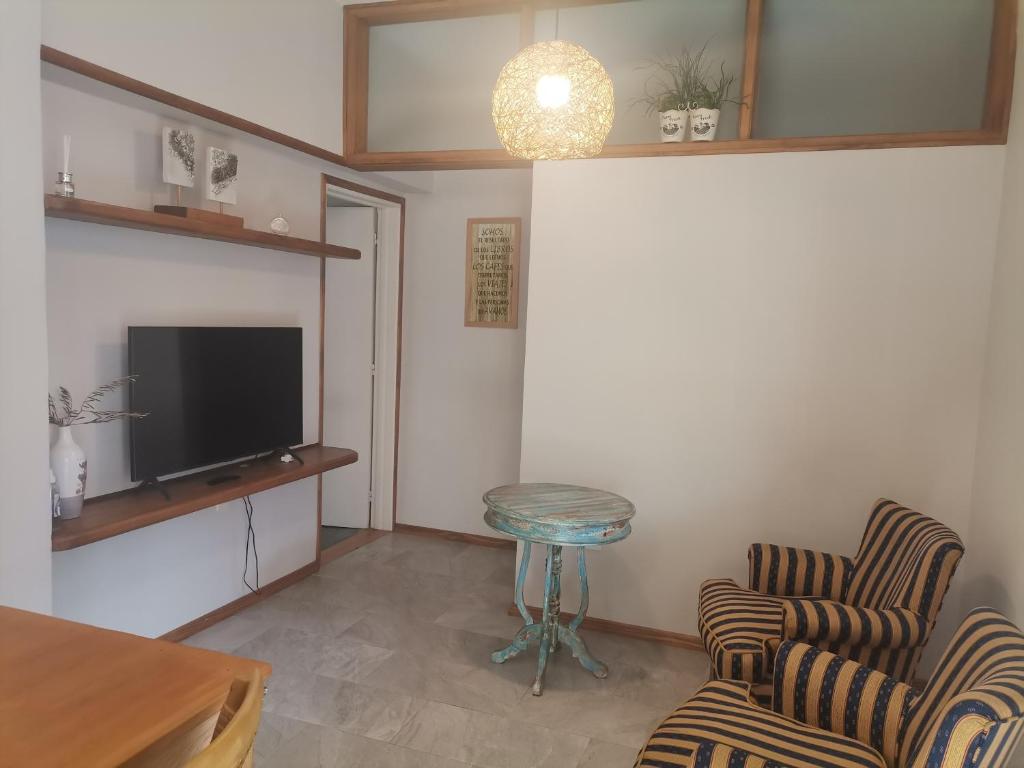 杜拉斯诺MANDALA HOME的客厅配有两把椅子、一张桌子和一台电视