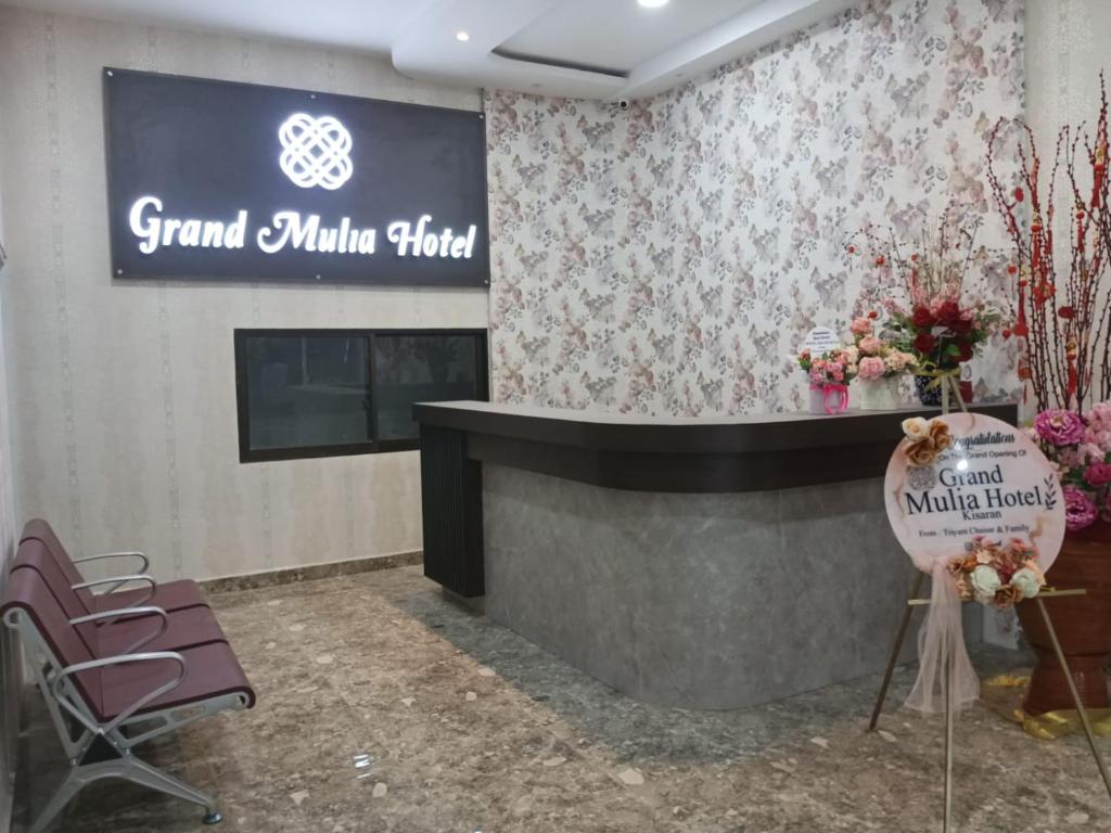 KisaranGrand Mulia Hotel Kisaran的一个带墙上标志和椅子的沙龙