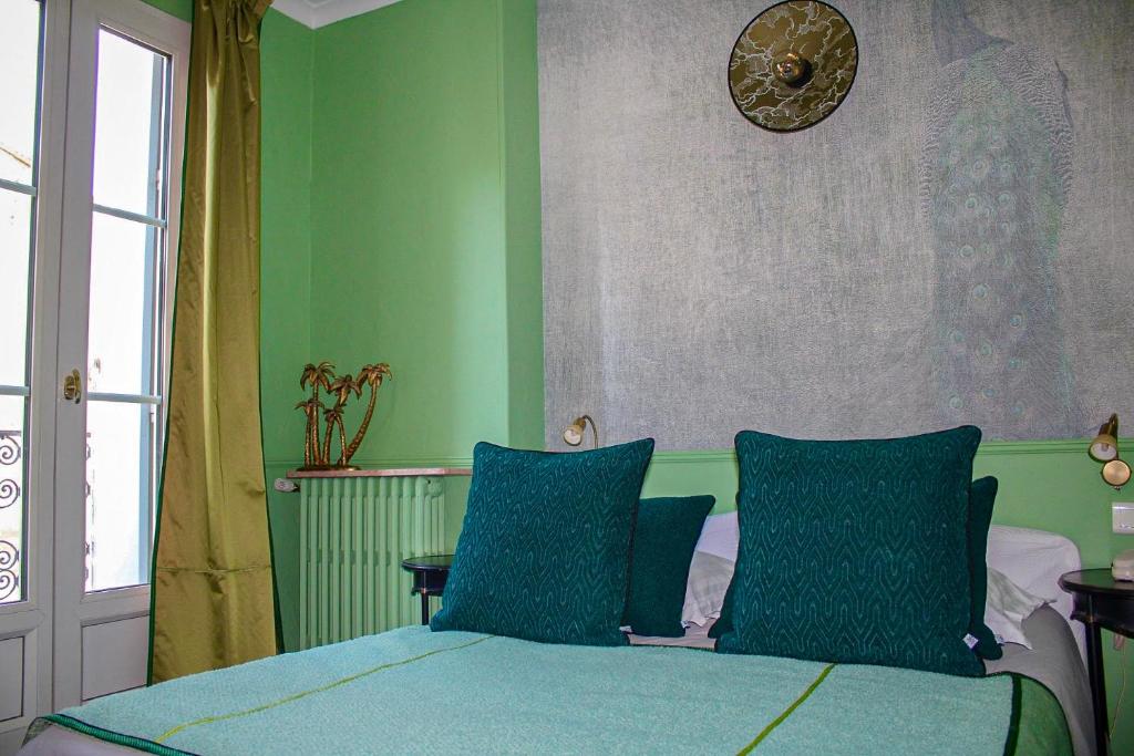 蒙彼利埃宫殿酒店的一间卧室设有绿色的墙壁和一张带蓝色枕头的床。