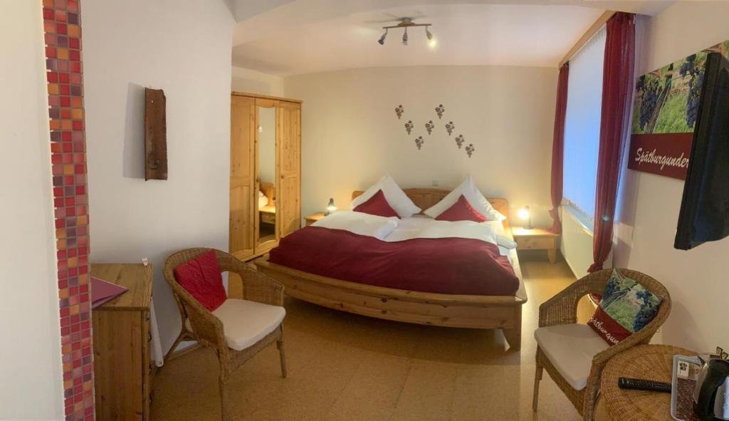 韦因斯特拉塞地区瓦亨海姆彼得酿酒厂旅馆的一间卧室配有一张大床和两把椅子