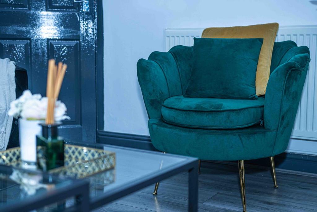 达德利Luxurious 5-Beds House in Dudley的客厅配有一张绿椅和一张桌子