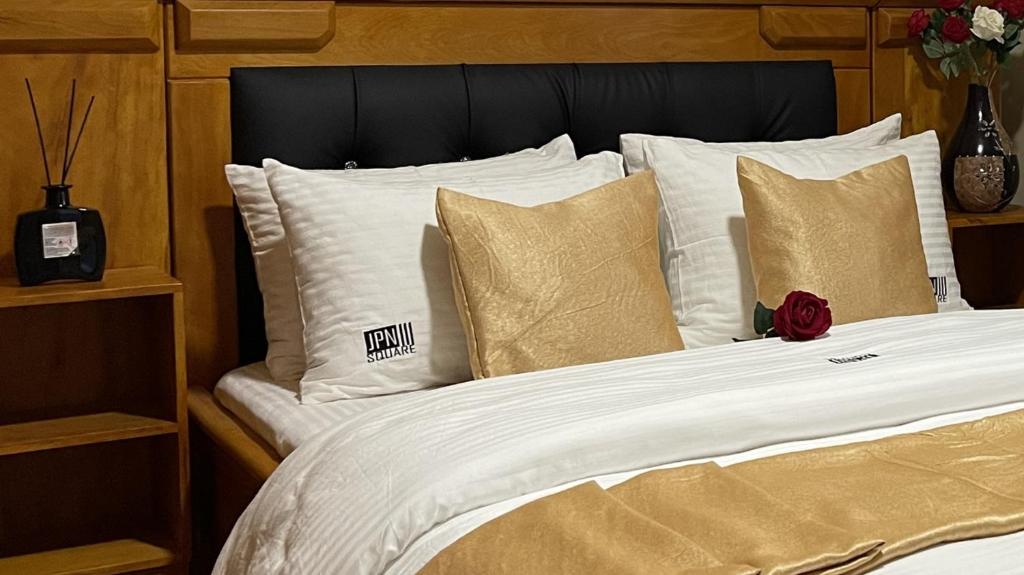 杜阿拉JPN SQUARE Douala的一张带白色床单和金色枕头的床