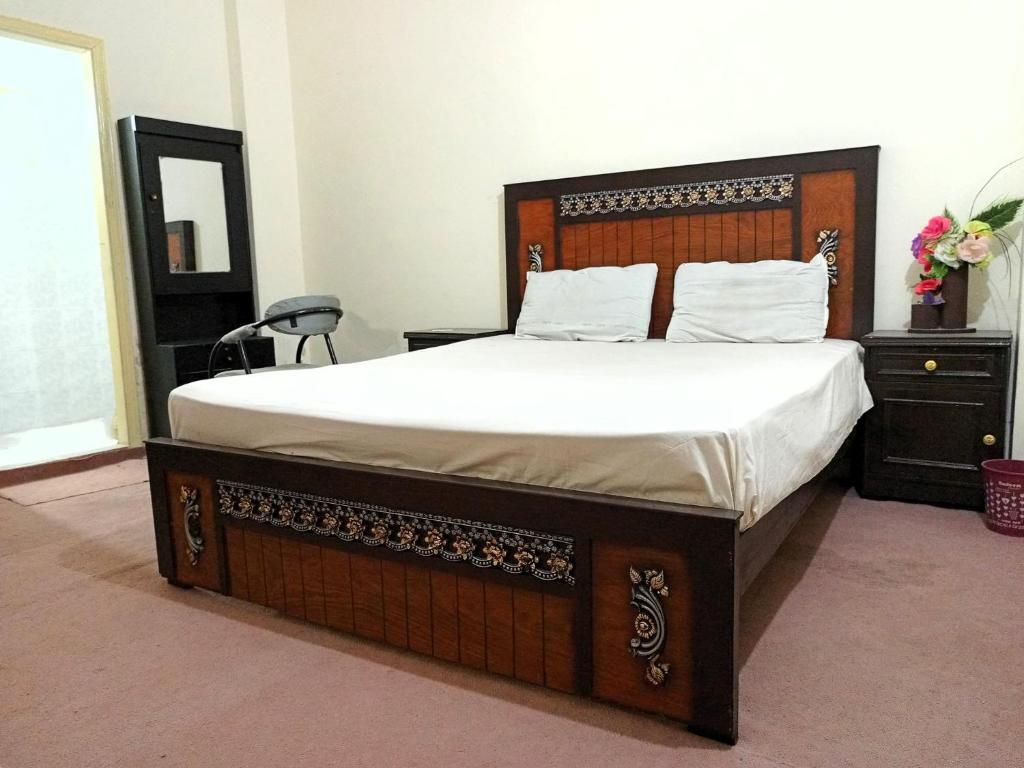 伊斯兰堡Stay Inn Islamabad的一间卧室配有一张大床和木制床头板