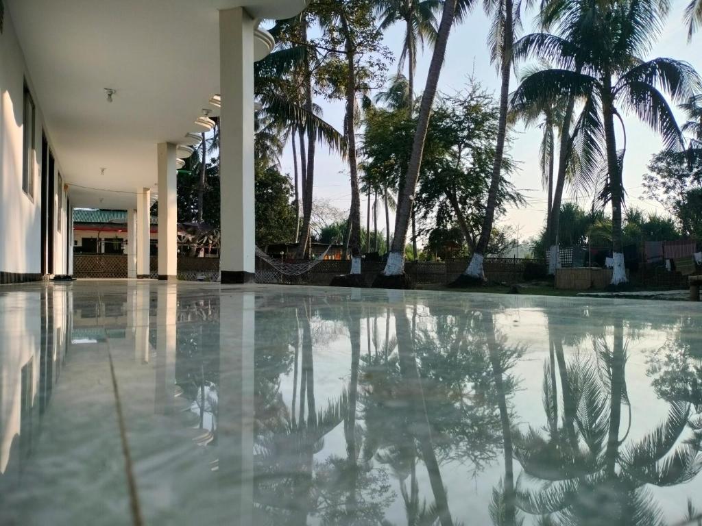 JaliapāraSurjasto Resort的一个棕榈树的空游泳池