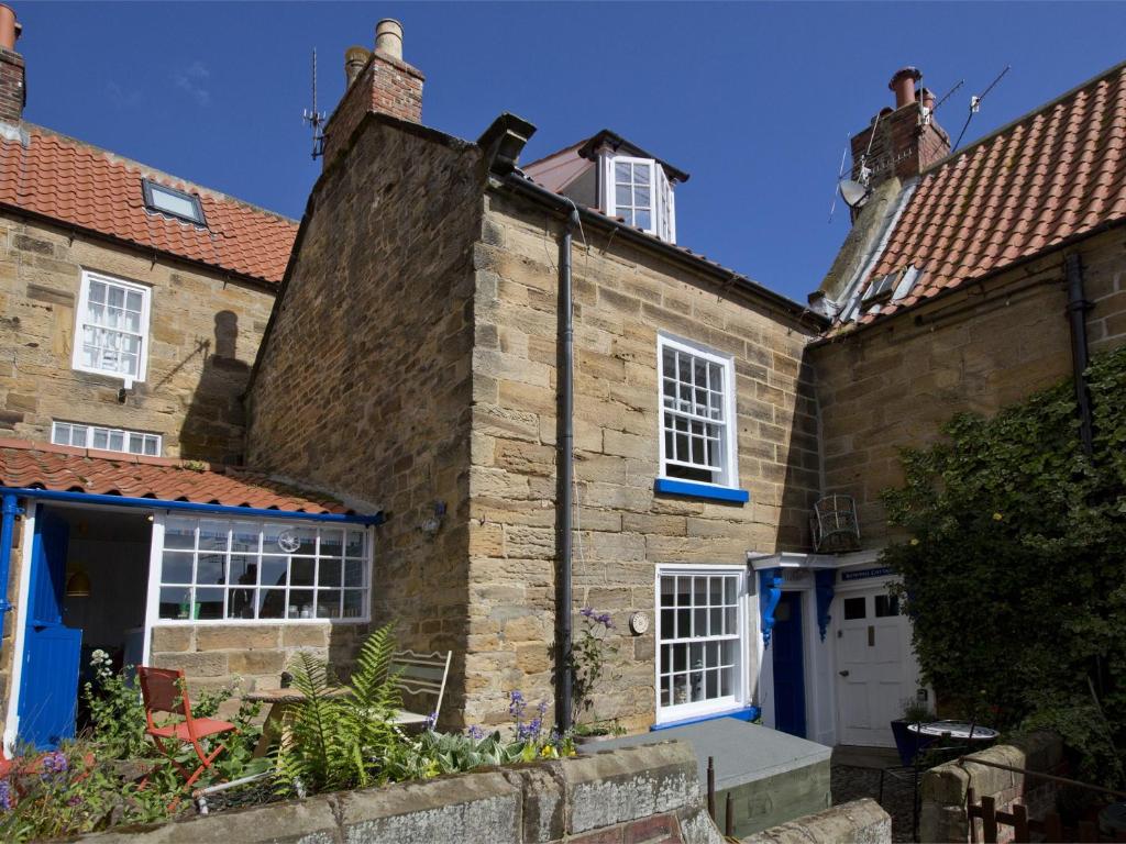 罗宾胡兹贝2 Bed in Robin Hoods Bay G0085的一座古老的石头房子,拥有蓝色的门和窗户