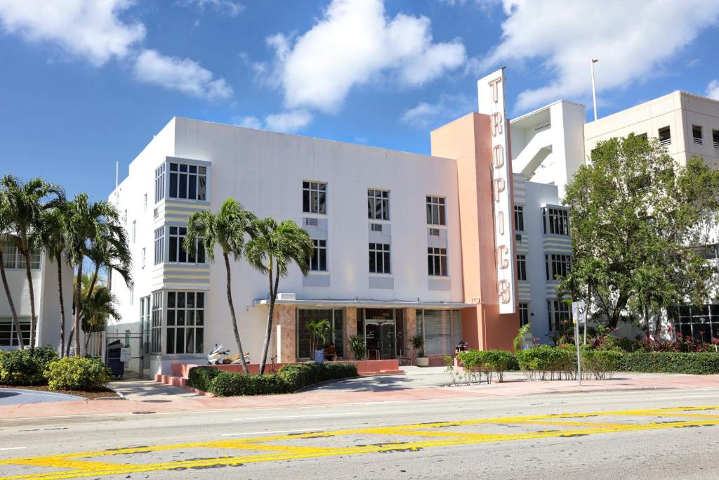 迈阿密海滩Tropics Hotel Miami Beach的一条街道前的白色建筑,棕榈树成荫