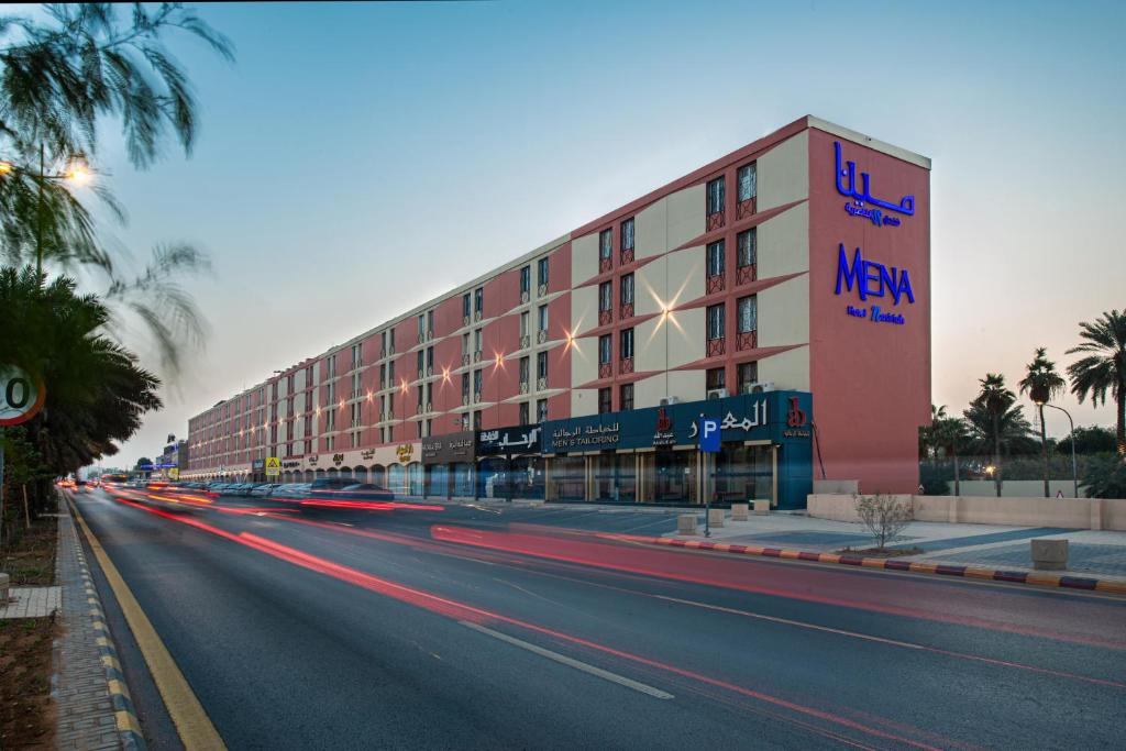 利雅德Mena Hotel Nasiriah Riyadh的街道边的汽车建筑