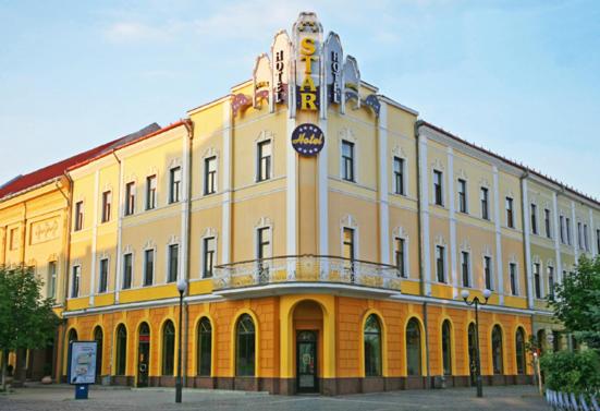 穆卡切沃Hotel Star的一座黄色的大建筑,上面有标志
