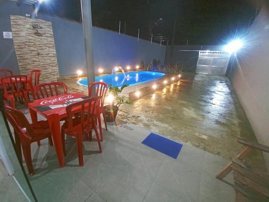 瓜鲁雅Casa com piscina, enseada Guarujá sp.的一张桌子和椅子,晚上还有一座游泳池