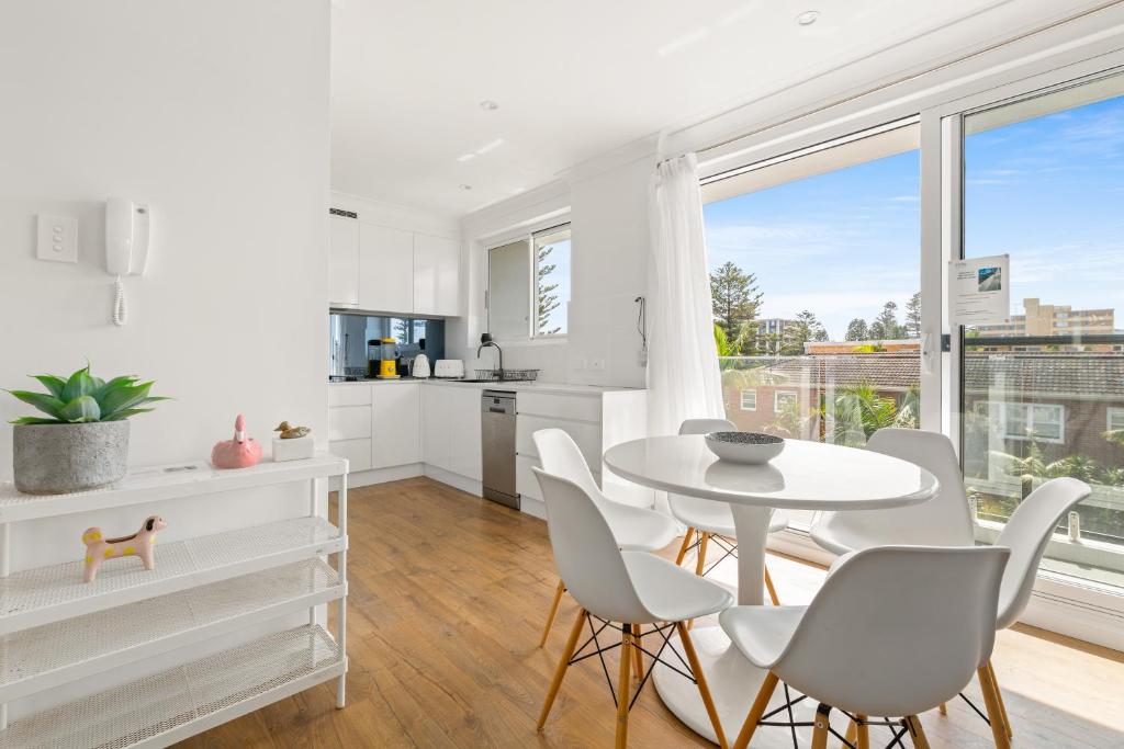 悉尼Chic apartment footsteps from Manly Beach的厨房以及带桌椅的用餐室。