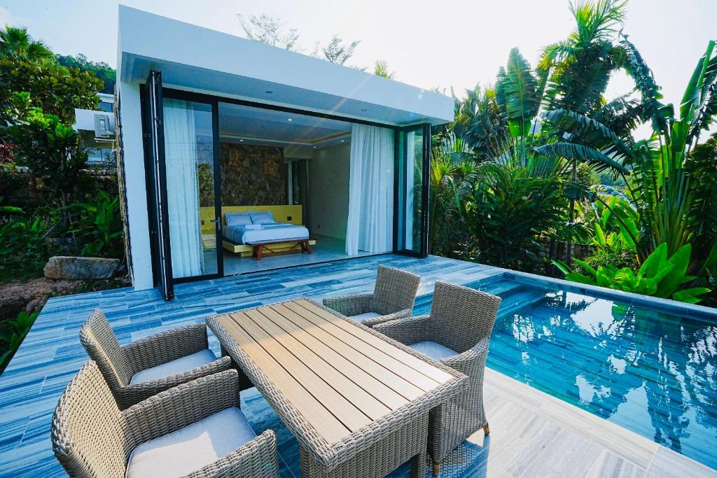 富国Kiwuki Beachfront Villa的甲板上配有木桌和椅子的房子