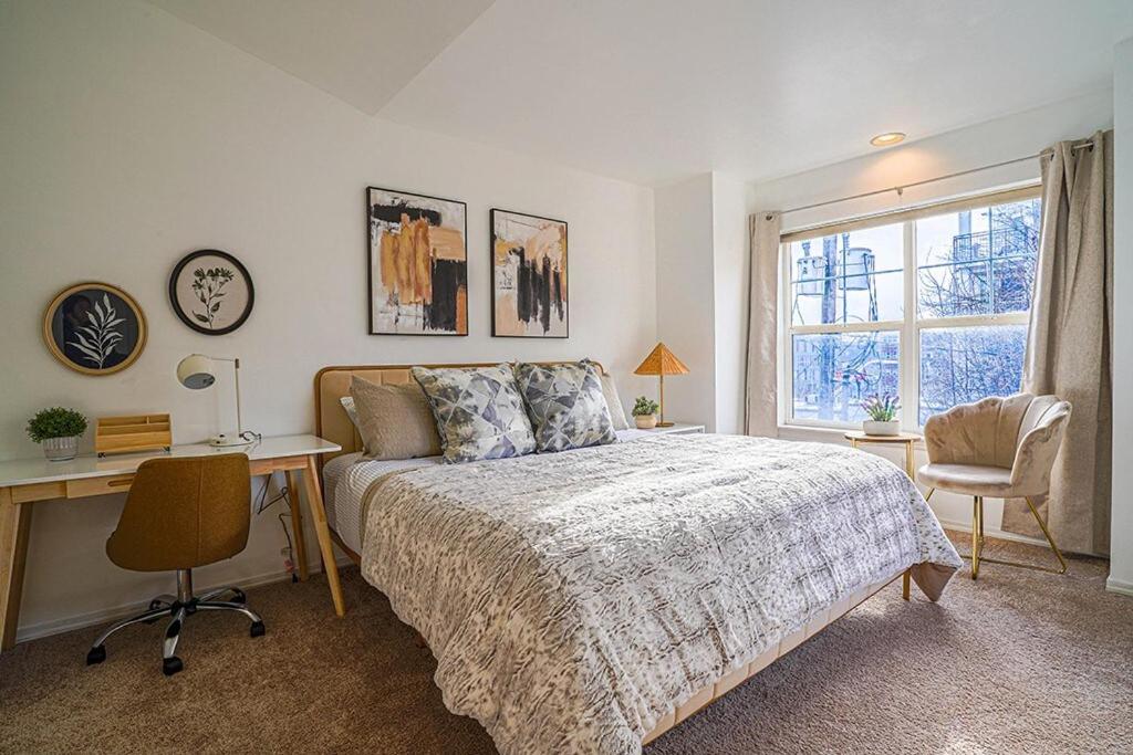 西雅图Ballard's Townhome with office & walk score 98的一间卧室配有一张床、一张书桌和一个窗户。