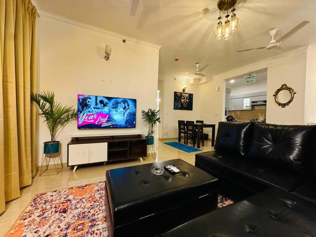 勒克瑙Celestial Chic Suite With Swimming Pool的客厅配有黑色沙发和平面电视。