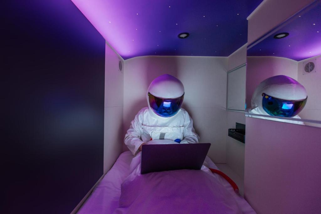 利沃夫Capsule Hotel Constellation 91的床上有笔记本电脑的人