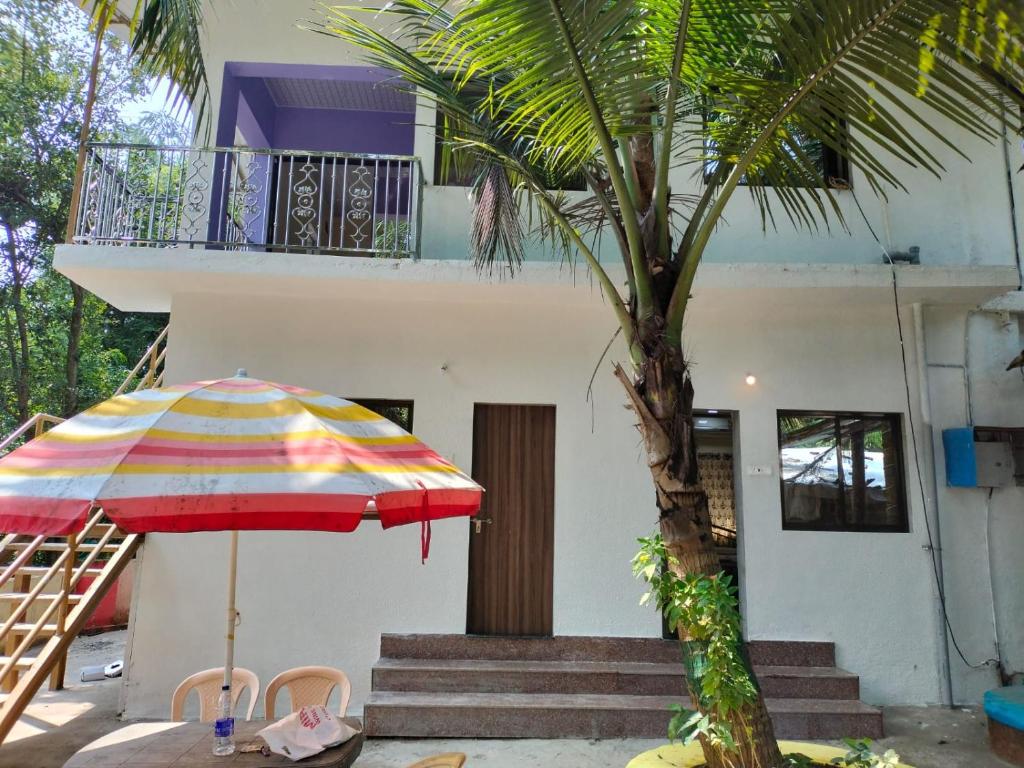 孟买Vellankani Resort Gorai的一座房子前面的一把色彩缤纷的伞和一棵棕榈树