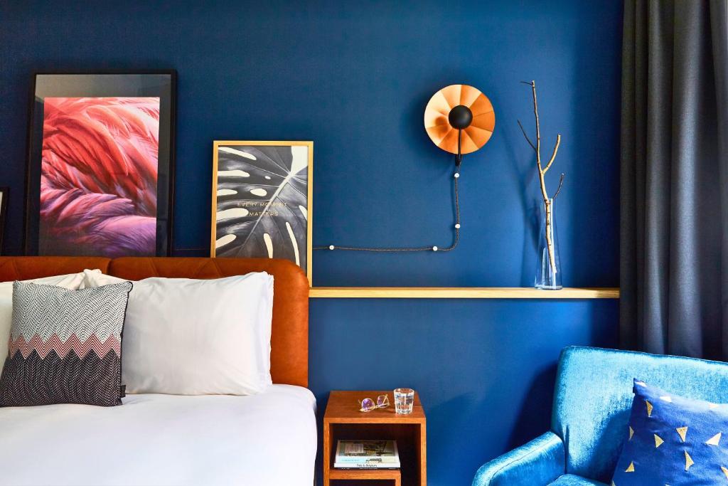 安特卫普安特卫普市中心英迪格酒店的一间卧室设有蓝色的墙壁、一张床和一把椅子