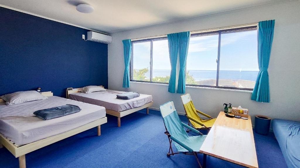 大岛QUENOS的一间设有两张床、一张桌子和一把椅子的房间