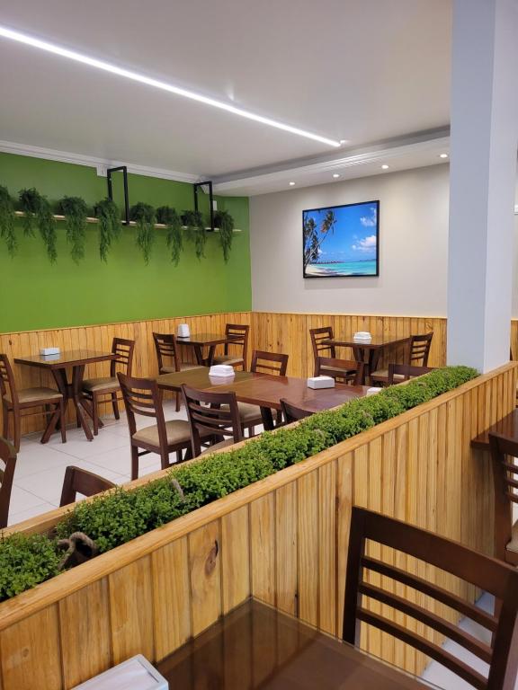 马拉戈日Pousada Concha Dourada的餐厅设有木桌和椅子,拥有绿色的墙壁