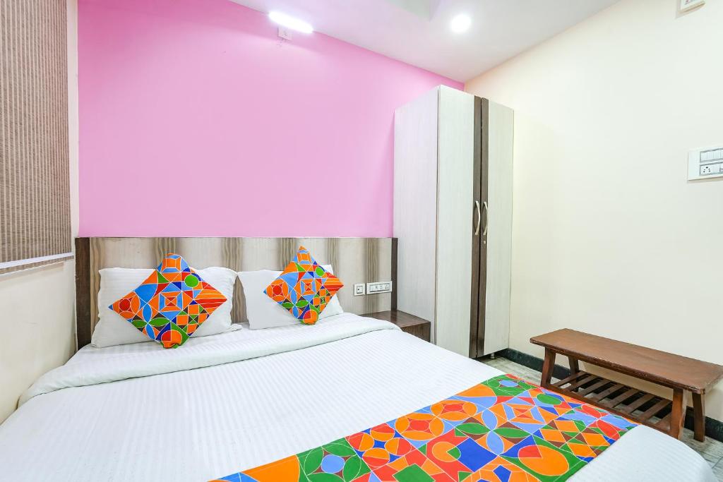 钦奈FabExpress Raj Supreme Residency的卧室配有白色的床和色彩缤纷的枕头