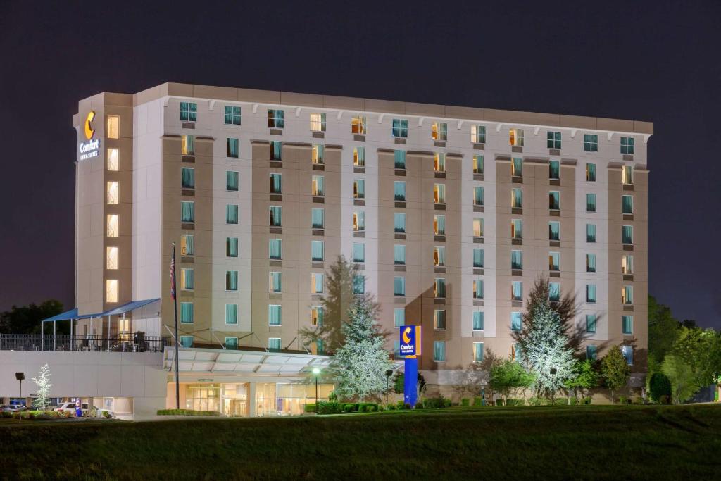 小石城康福特茵总统套房酒店的一座白色的大建筑,晚上有灯光