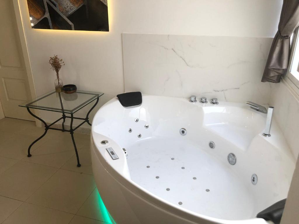 赫雷斯-德拉弗龙特拉Apartamentos Las Naranjas的浴室设有白色浴缸,配有玻璃桌