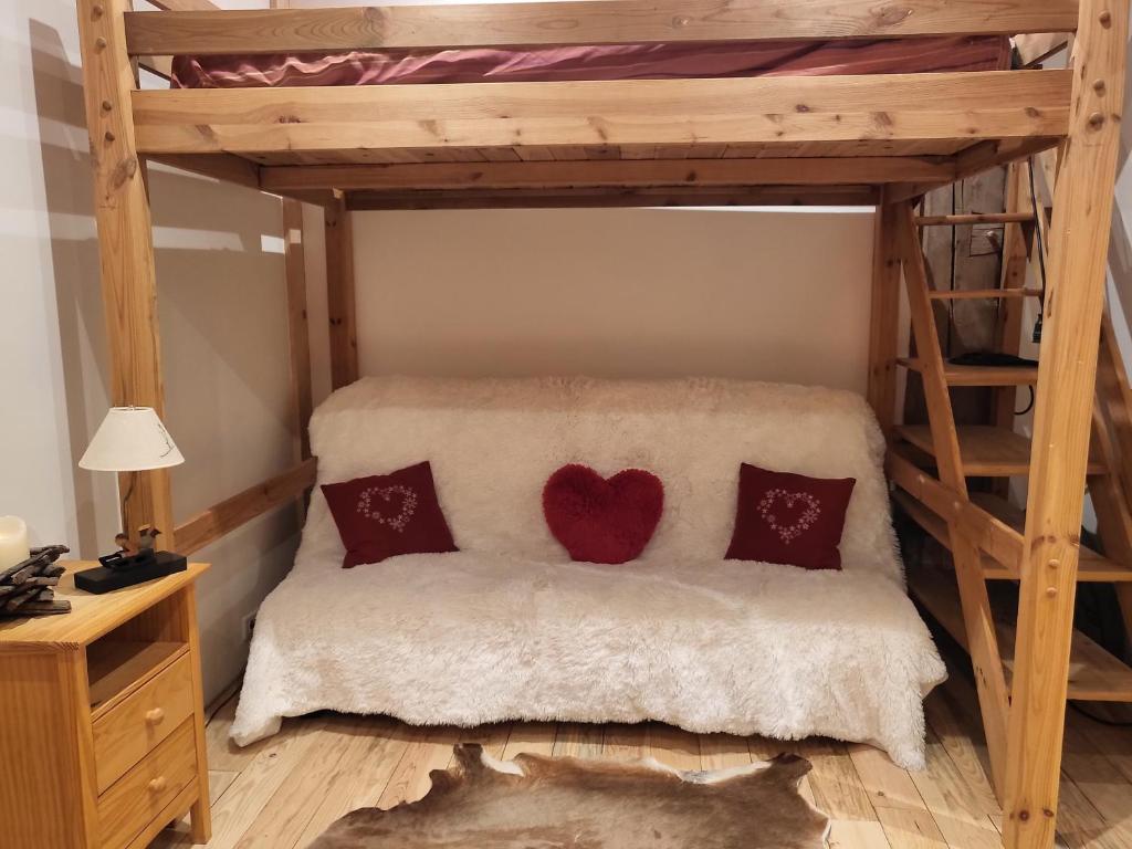 伊斯特若曼德Le Nid des Cerfs的一间卧室配有高架床和两个红色枕头