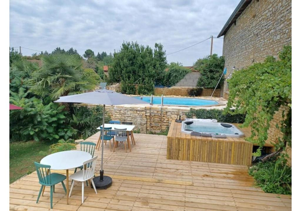 La PoterieNid Charentais Angouleme pool jacuzzi的一个带桌子和遮阳伞的庭院和一个游泳池