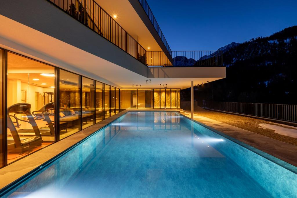 拉瓦莱Hotel Alpenrose Dolomites的房屋中间的游泳池