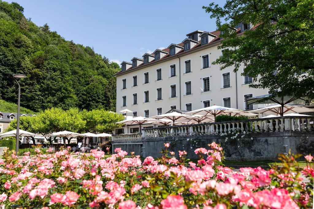 于尔亚日莱班Grand Hôtel & Spa Uriage的一座大建筑前面有粉红色的花朵