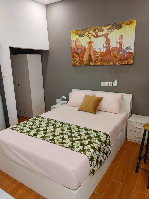 KpaliméLES 9 PLURIELLES - Studio 5的卧室配有一张白色大床,墙上挂有绘画作品