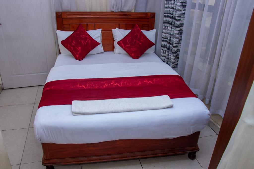 内罗毕Epitome Times Hotel的一张带红色枕头和红色毯子的床