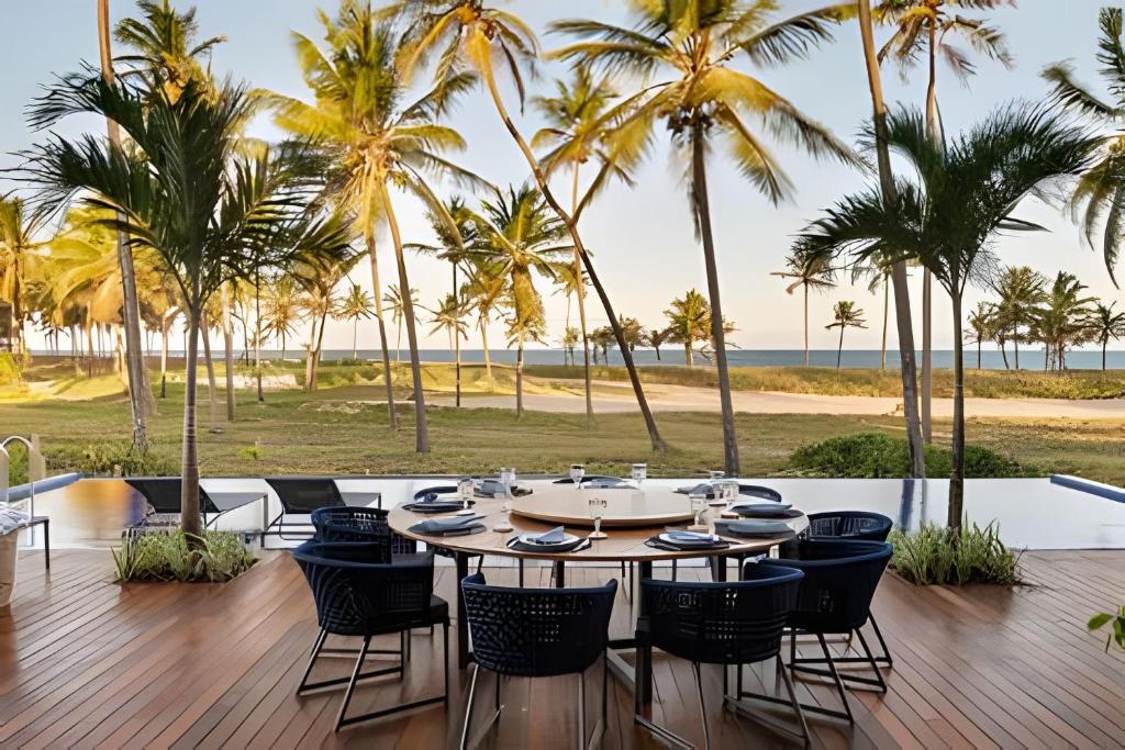 普拉亚多Luxo a 50 m da praia, acesso ao Iberostar Resort的棕榈树甲板上的桌椅