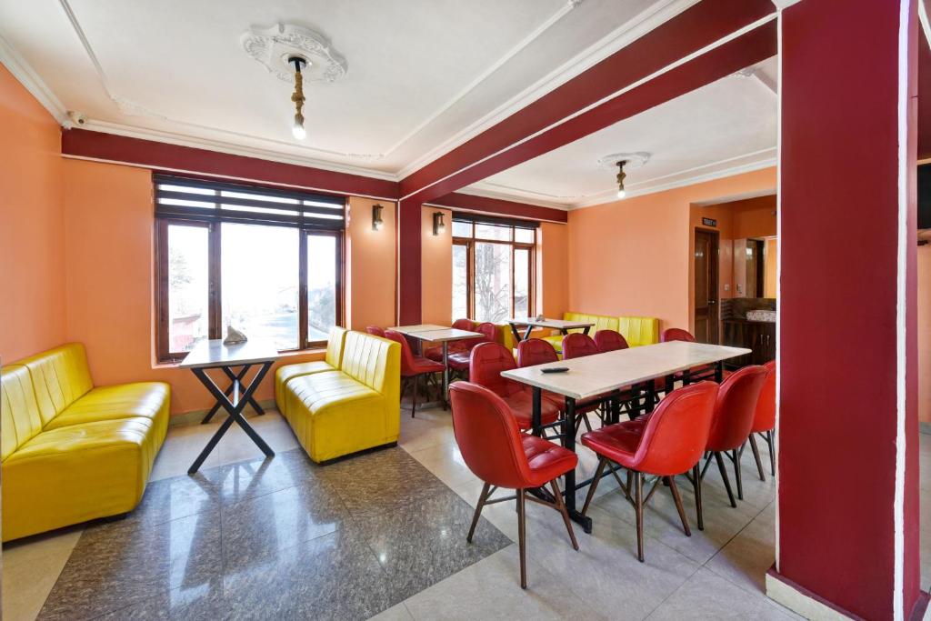 西姆拉Woods Imperial Kufri的餐厅拥有橙色的墙壁和桌椅